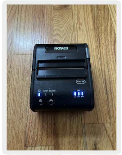 The receipt printer showing a blue light indicating that it's on